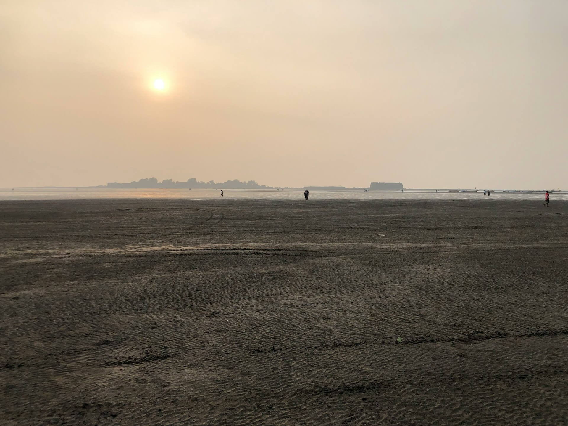 Visitors walking along Alibaug beach at sunset in Maharashtra